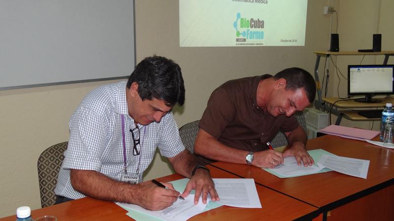 El director de la Dirección de Transferencia de Tecnología MSc. Rafael Torralbas Ezpeleta y el Lic. Eulogio Pimentel Vázquez, director del Centro de Ingeniería Genética y Biotecnología realizan el intercambio de firmas para nuevos convenios de trabajo UCI-BioCubaFarma. 